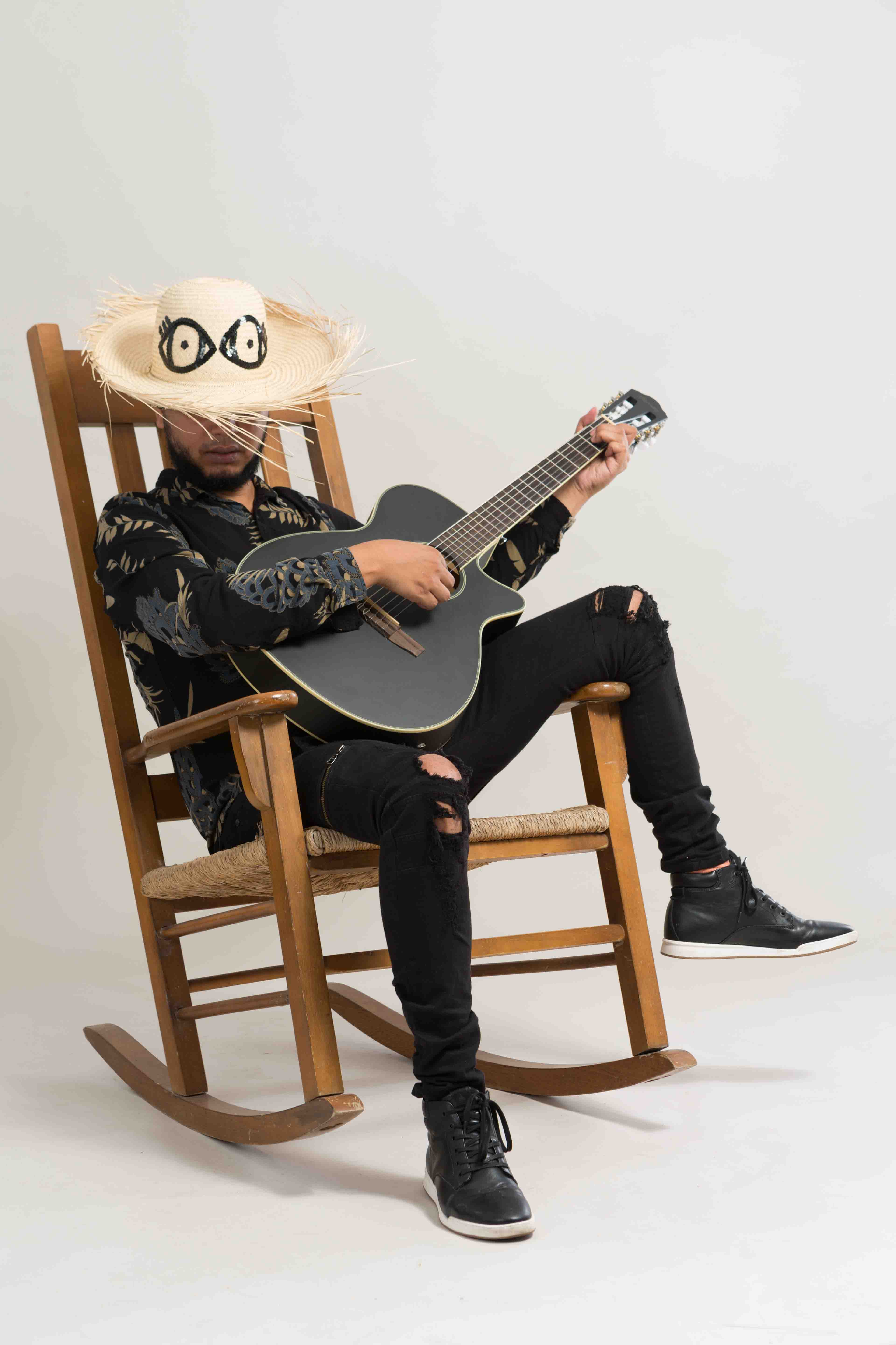 Janio Lora en mecedora con guitarra